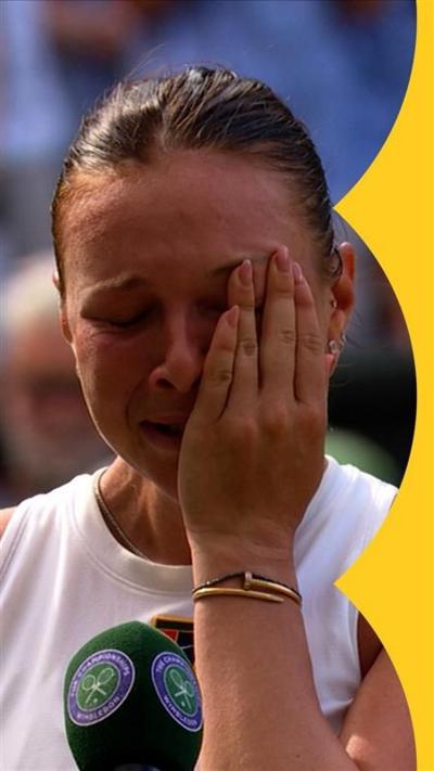 Amanda Anisimova wipes a tear away at Wimbledon. She is wearing a white, sleeve-less top and has brown hair.