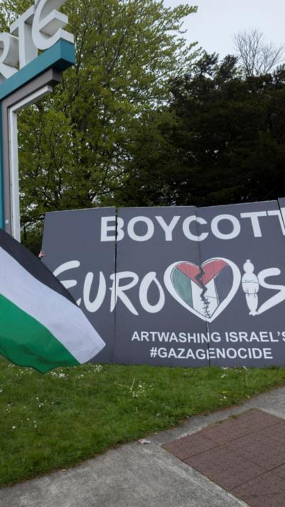 A past a sign which reads 'Boycott Eurovision.