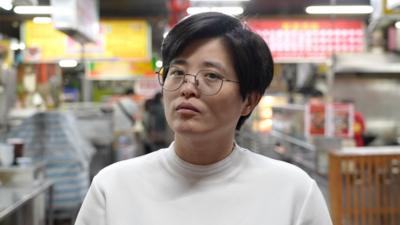 Yang Shuang-zi standing in a food court