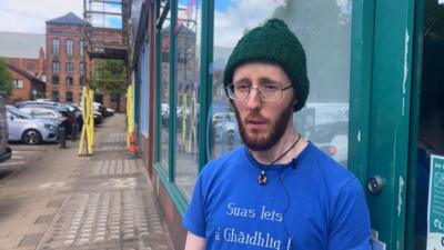 Andy Beck, Ionmhasair An Lòchran na sheasamh taobh a-muigh an togalach.