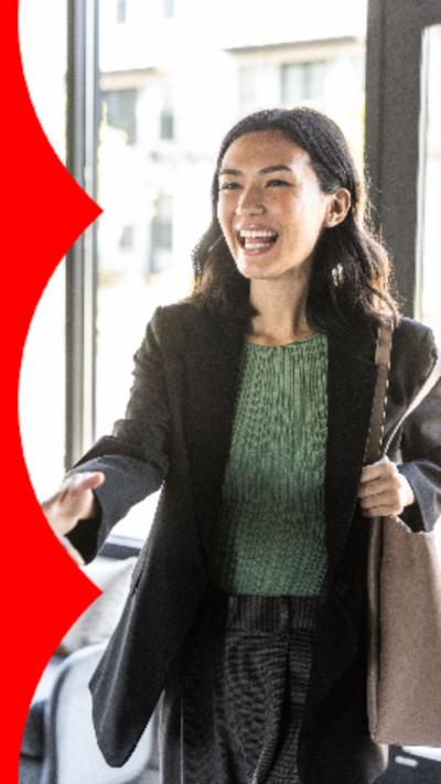 g woman with long dark hair wearing a blazer over a green top, shaking someone's hand.