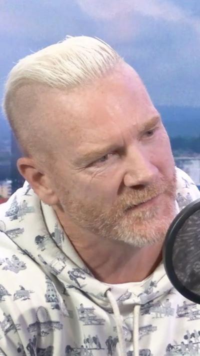 Iwan Thomas MBE sits in the Radio Solent studio. He has a white mowhawk combed back and a ginger and white short beard. he is wearing a white hoodie with a dark blue print.