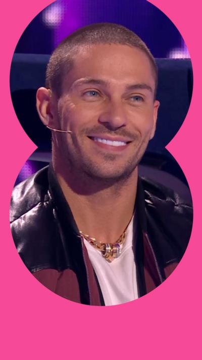 Close crop of Joey Essex, with a shaved head, smiling, on a gameshow set.