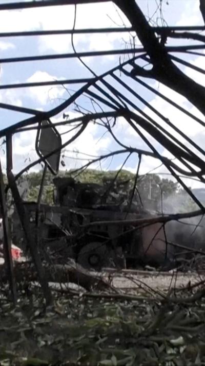 Screengrab shows a damaged vehicle, with smoke coming out of it, and a damaged fence