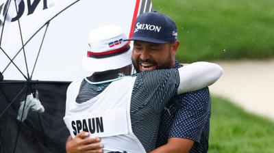 JJ Spaun smiles and hugs his caddie Mark Carens on the golf course