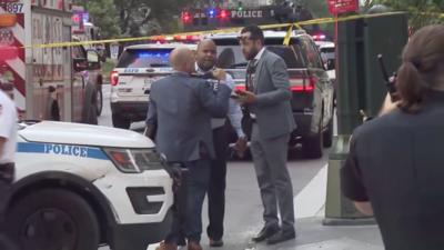 Police are standing outside the site of the Manhattan shooting, surrounded by police tape, flashing lights and vehicles.