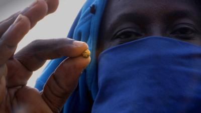 An illegal miner holding a gold nugget