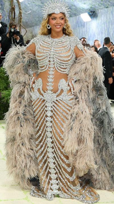 Beyonce wears a sparkly skeleton-outlined gown with a fur-like long cape and a bedazzled crown.