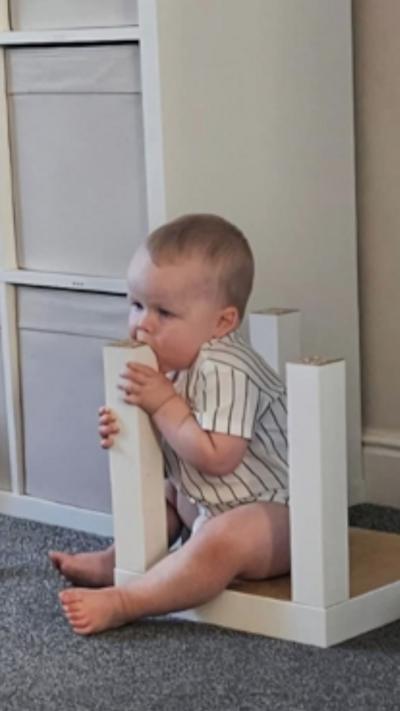 A baby eating a table leg