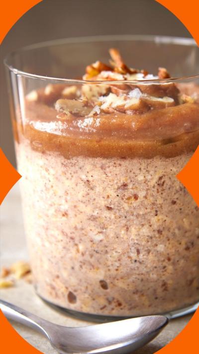 A circular glass container of overnight oats with a sticky toffee top layer and pecan garnish 