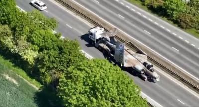 A Buccaneer fighter jet on the back of a lorry makes its way along a dual carriageway
