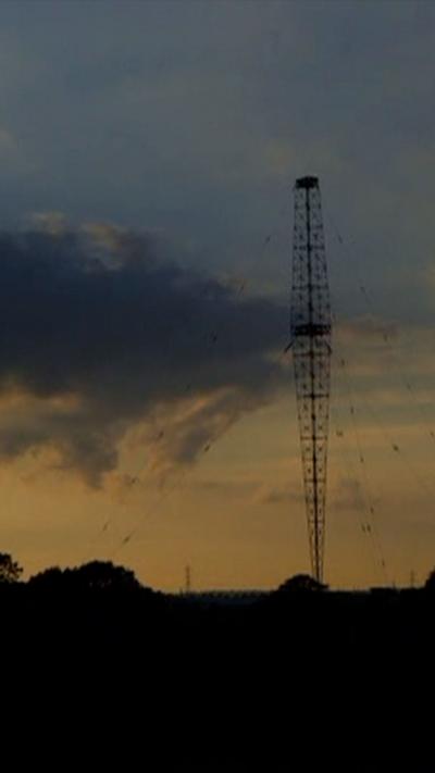 a metal transmitter silhouetted against a sunset sky
