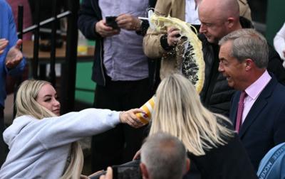 A woman throws contents of a drinks cup in Farage's face