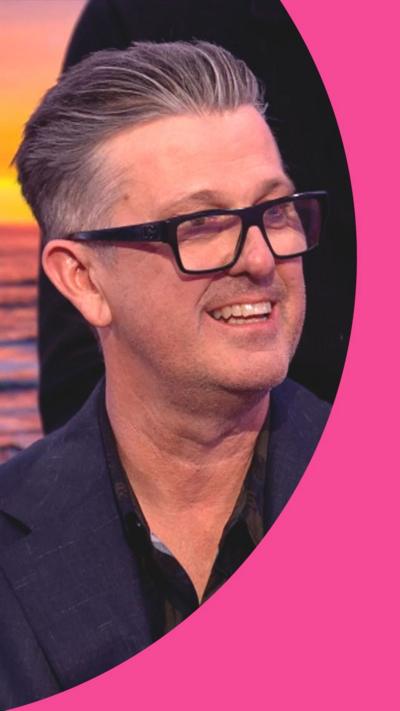 David McCormack, the voice of Bandit Heeler, smiles. He wears black glasses and has swept back grey hair.