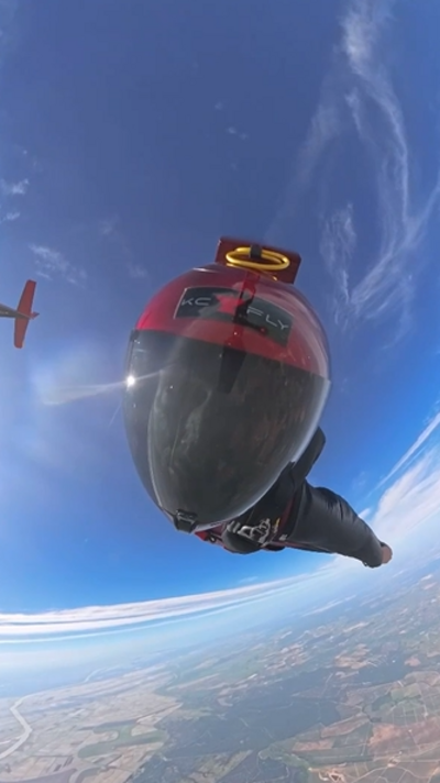 Casey Flay wearing a wingsuit and helmet and flying in the sky