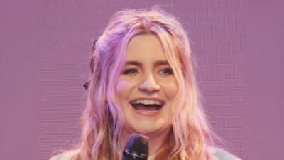 Harriet Kemsley smiles. She has long wavy blonde hair.