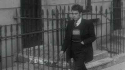 A Teddy Boy walking down the street.