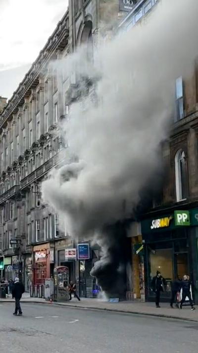 Large plumes of grey smoke emitting from retail shop on Union Street with bystanders looking on