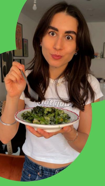 A woman holds a fork over a plate of food
