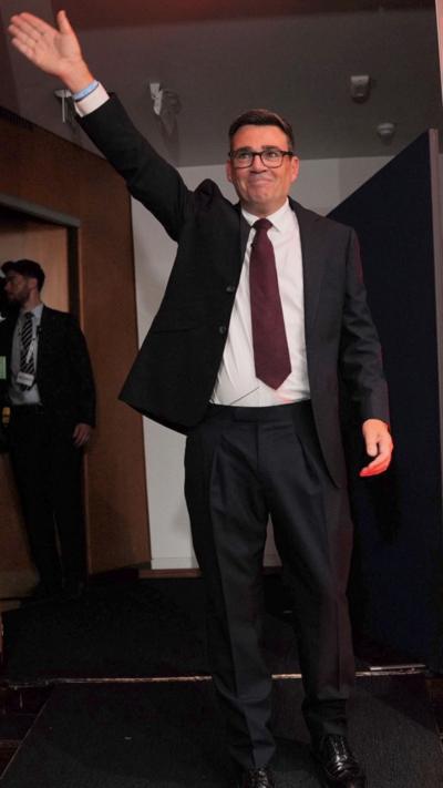 Andy Burnham waving dressed in a suit
