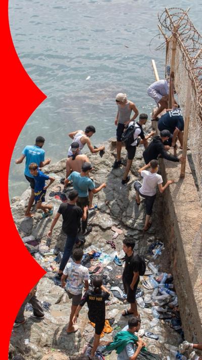 Men climbing wall by the sea
