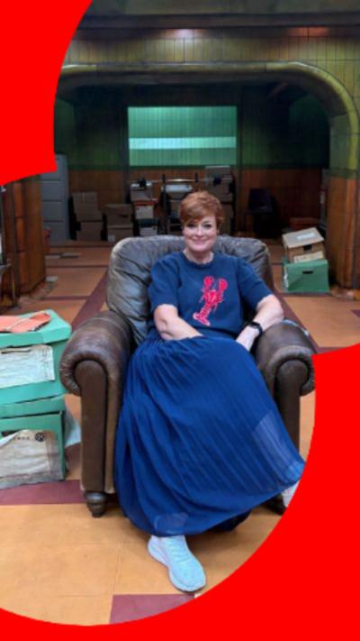Woman with blue skirt and auburn short hair smiling
