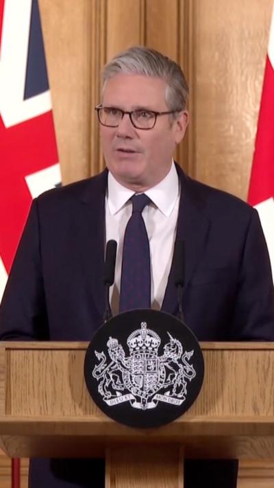 Sir Keir Starmer speaking a podium next to a Union Jack flag