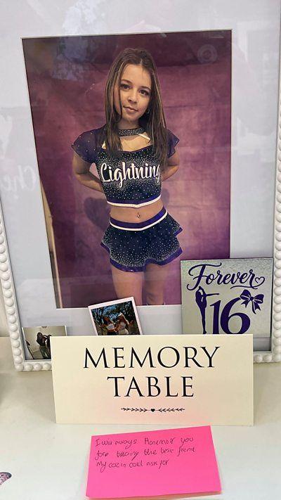 A memorial table for a 16-year-old girl in a cheerleading uniform.