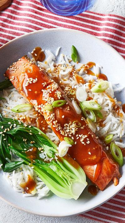 Top down view of a trout with sesame seed sprinkled on it on a bed of rice