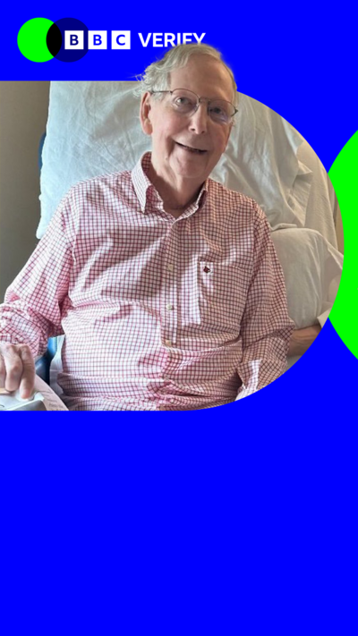 Senator Mitch McConnell smiles wearing a pink shirt and sitting in a hospital bed 