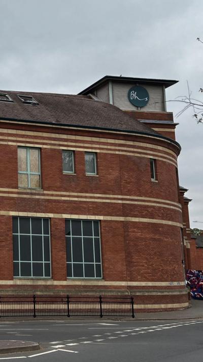 A two storey brick building on a road junction. A tower includes a logo for BHS