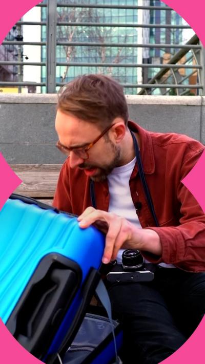 Harry Kind crouches down on the floor as he opens a blue suitcase.