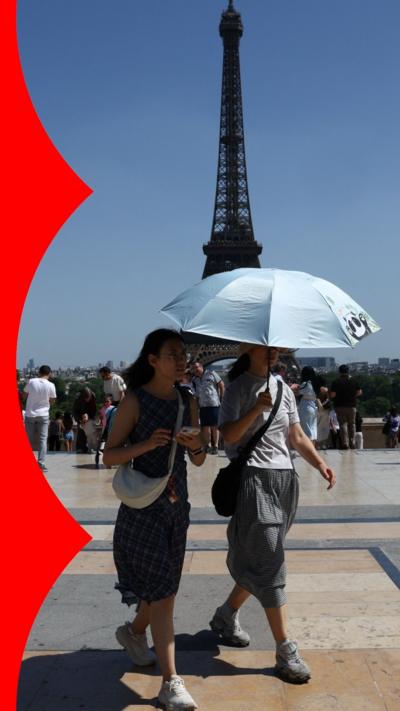 People shelter under an umbrella near the Eiffel Tower 