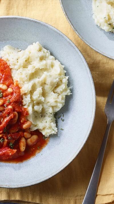 A bowl of smokey tomato bean stew served with creamy cauliflower mash