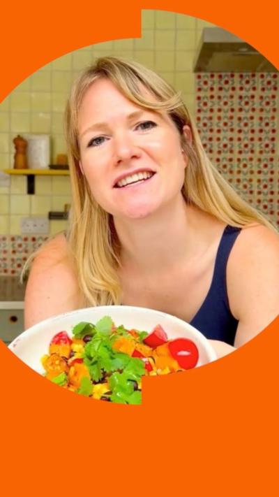 A woman with blonde hair holds a bowl of salad