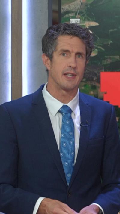 BBC weather presenter wearing navy suit, blue tie and white shirt