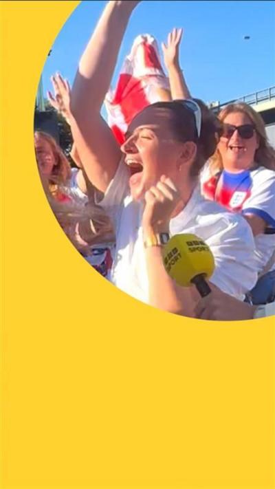 A woman in an England T-shirt surrounded by other England fans dancing and chanting