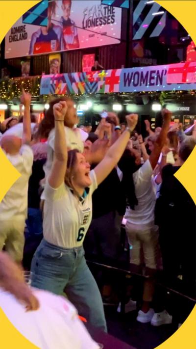 A crowd of England fans with their arms in the air