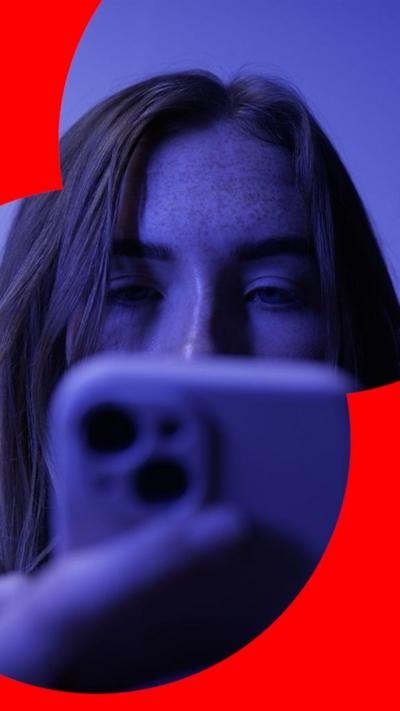 A woman with long hair looks down at her phone