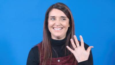 A woman holds up her left hand displaying her rings