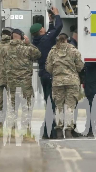 Members of the armed forces stand around the bank of a bomb disposal lorry