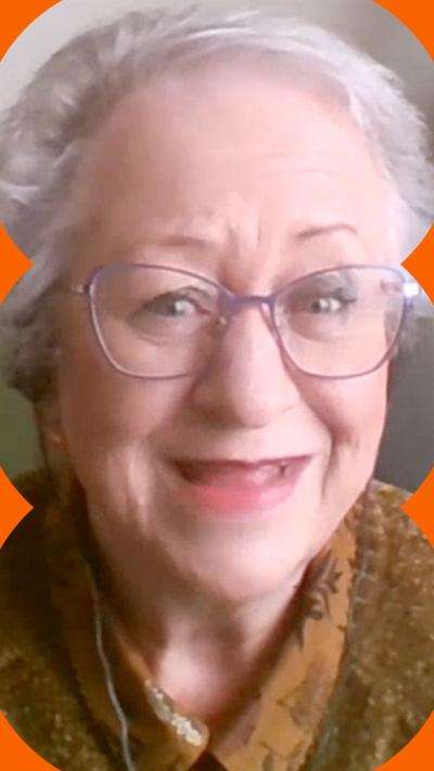 Jackie Weaver smiles at the camera, she has white hair and wears purple-rimmed glasses