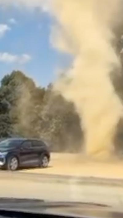 Dust devil swirling around car park between parked cars