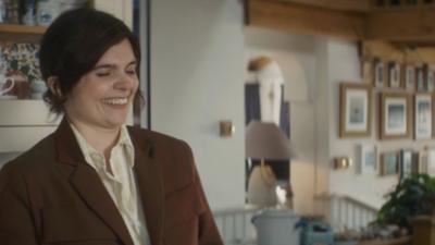 Death Valley character Detective Sergeant Janie Mallowan laughs. She wears a brown jacket and has her hair tied back