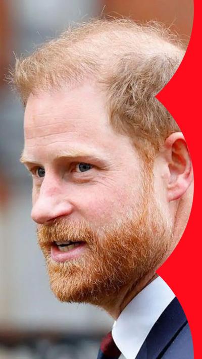 Close-up of Prince Harry, wearing a navy suit. He has a full beard and moustache, and ginger hair.
