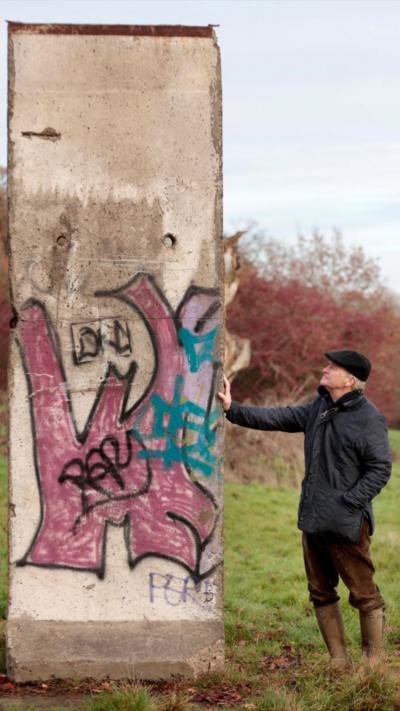 A man stood next to a piece of the Berlin Wall