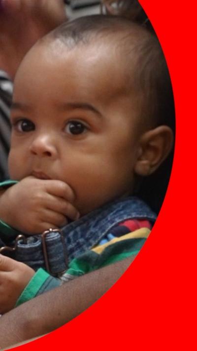 Baby Ezra sucking his thumb while sitting on his mum's lap in the Melodies for Mums class.