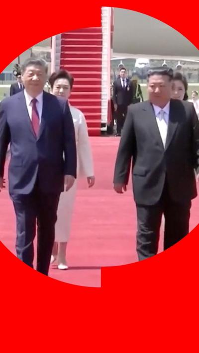Xi Jinping and Kim Jong Un walking side by side on tarmac