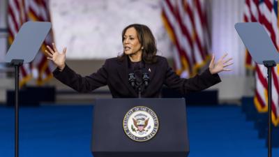 Kamala Harris holding her arms up at a podium.