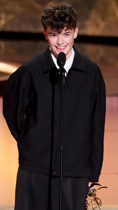Owen Cooper speaking into a mic on the Emmys stage. 